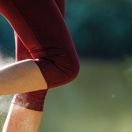 Person applying sunscreen on legs in a grassy field