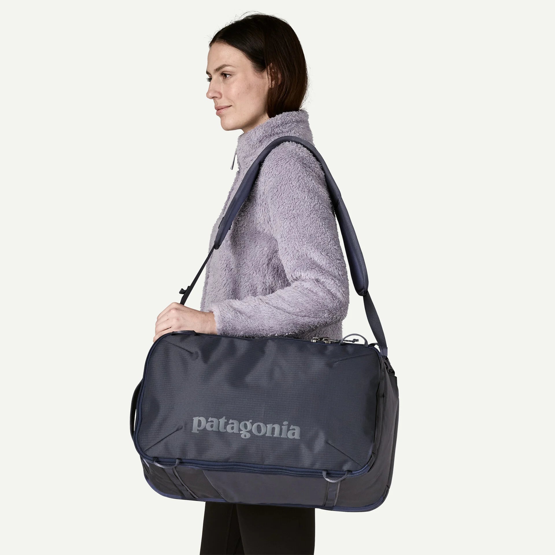 Woman carrying a Patagonia duffel bag on a white background