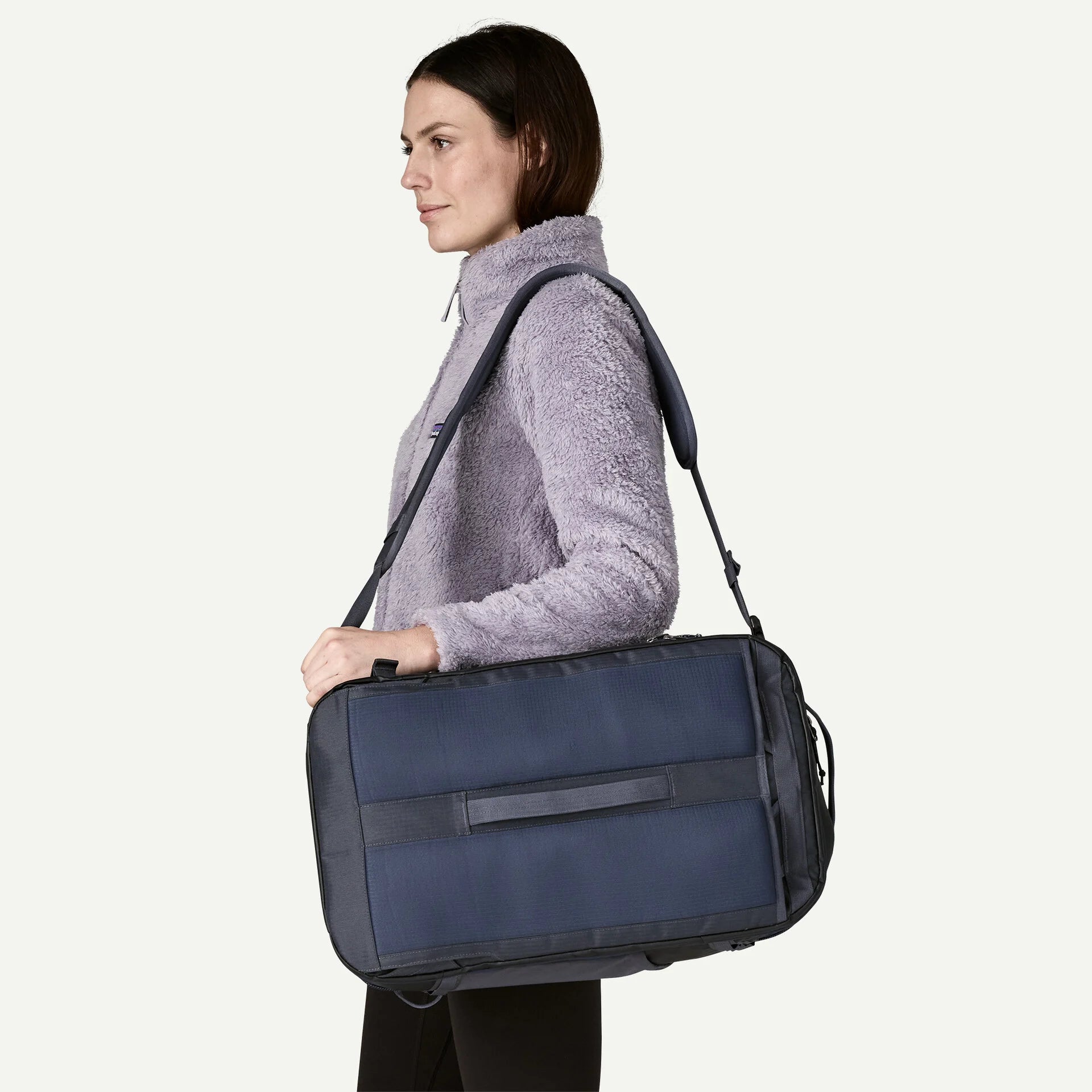Woman carrying a navy blue duffel bag on a white background