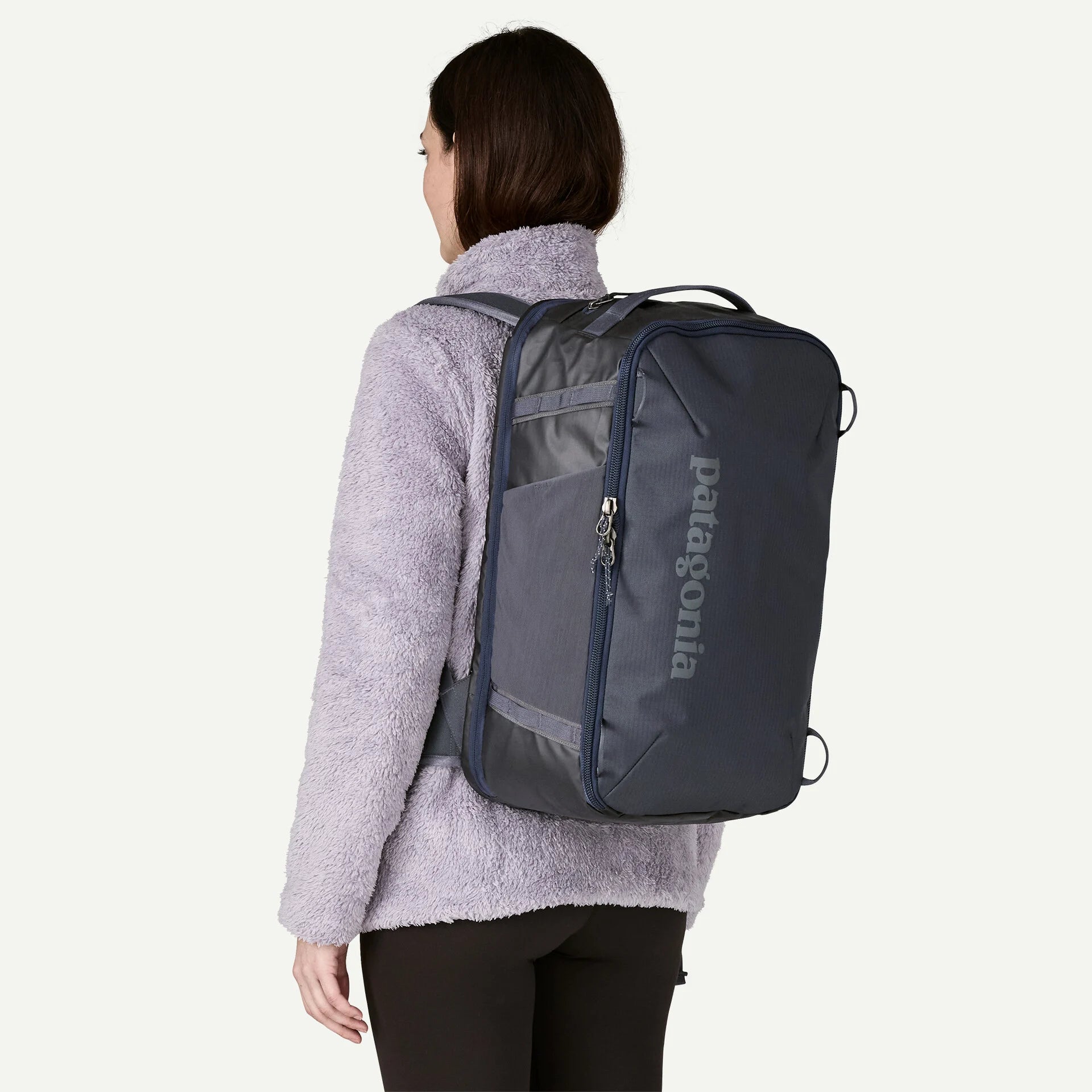 Person wearing a Patagonia backpack on a plain background